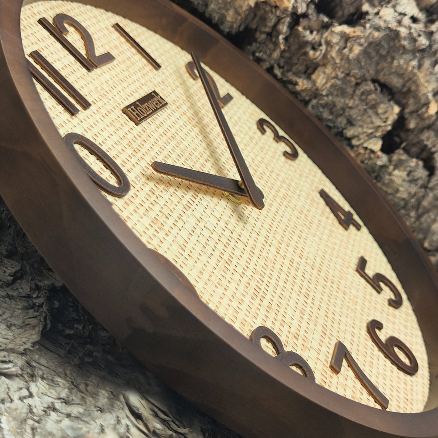 Schrägaufnahme der Holzwerk PENZBERG Quarz-Wanduhr aus Vollholz mit Rattan-Design und brauner Zeigerführung