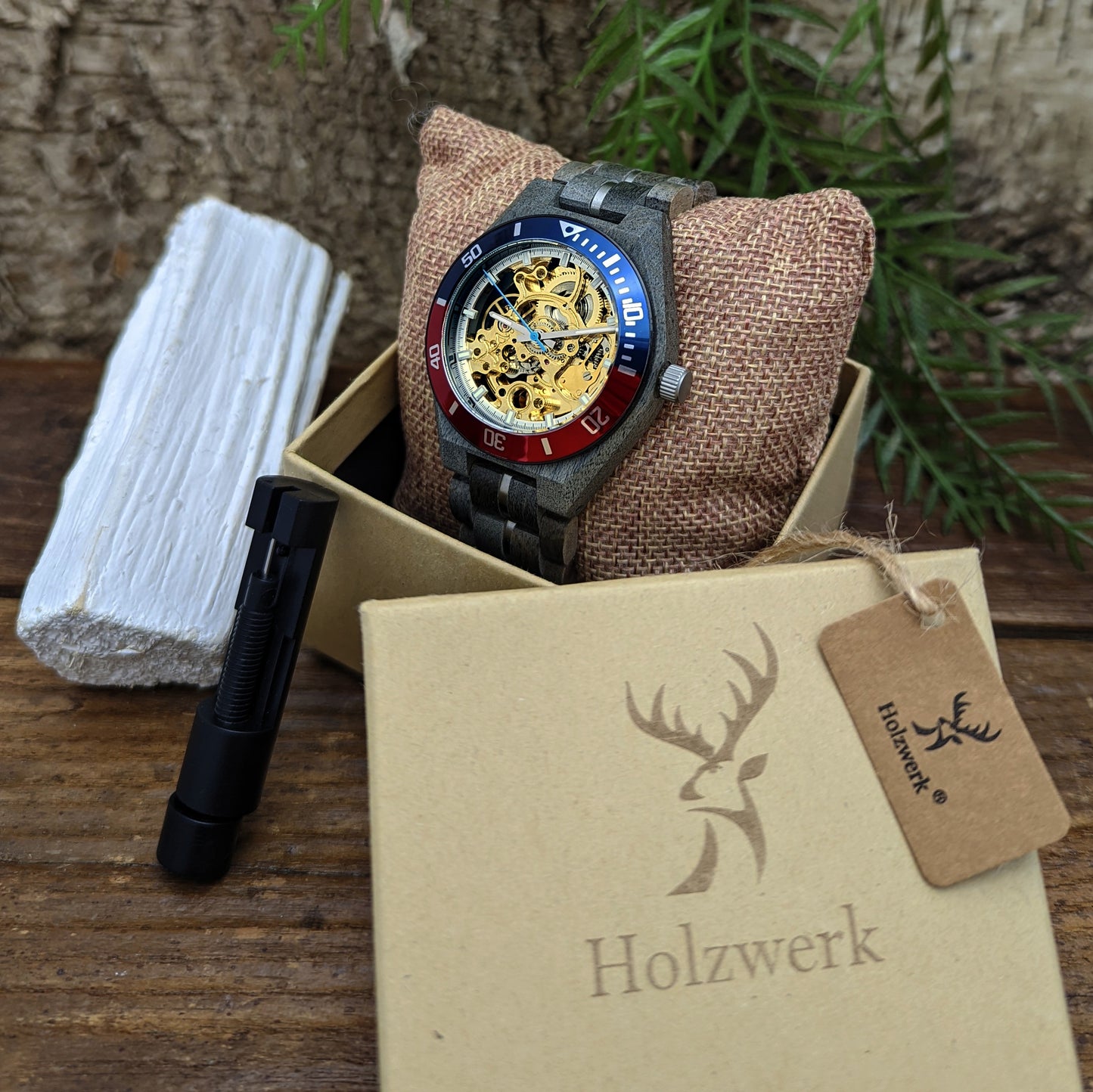 Holzwerk DELBRUECK Automatik-Uhr mit grau, blau und rotem Gehäuse sowie goldenem Ziffernblatt mit offener Unruhe in Holzwerk Verpackung
